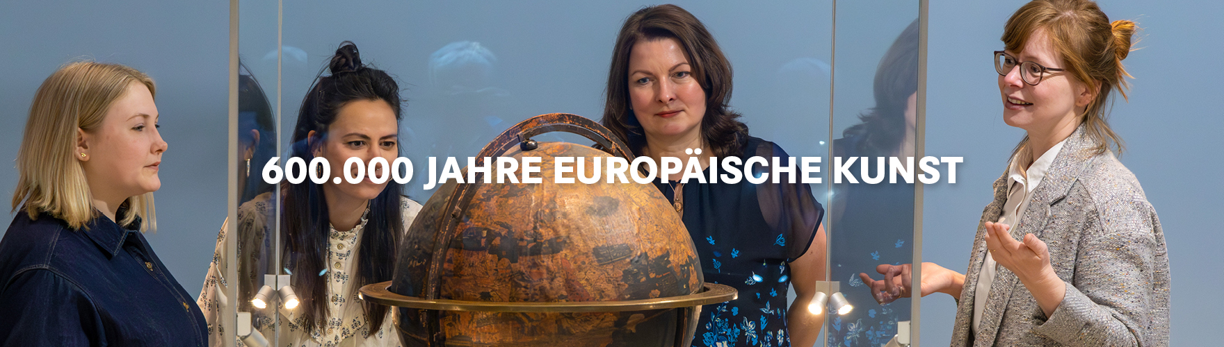 Vier Frauen stehen im den Behaim-Globus und betrachten ihn genau.