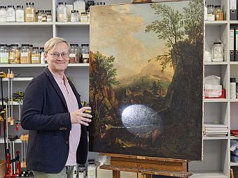 Benjamin Rudolph steht vor einer Staffelei mit einer Gemälde.